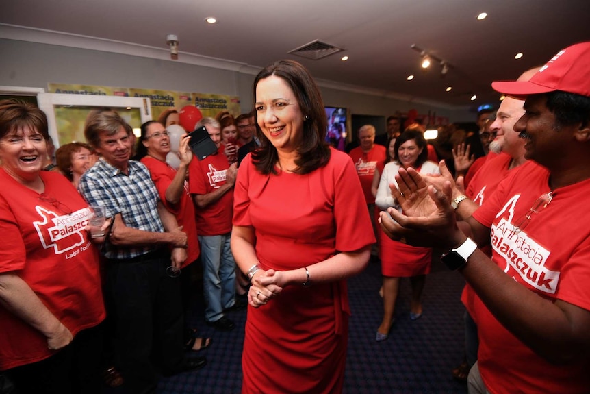 Annastacia Palaszczuk walks through a crowd of happy supporters all wearing red.