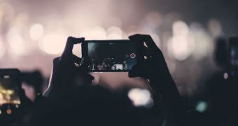 A phone is held aloft at a concert to record the proceedings.