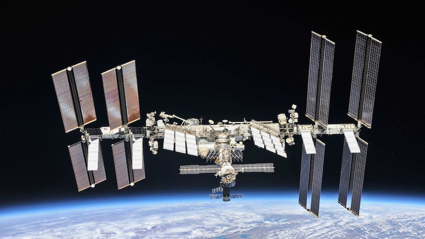 The International Space Station in orbit above the Earth, with solar panels unfurled, as seen from another craft