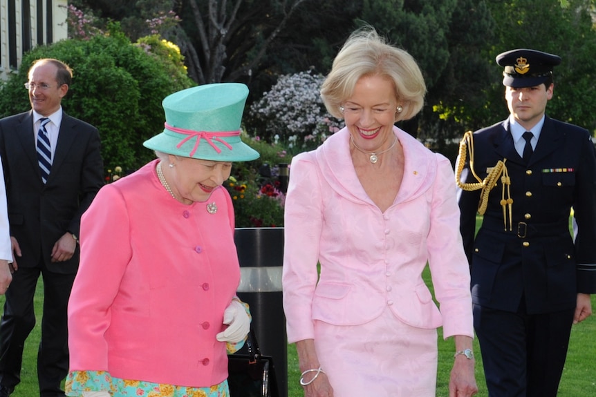 governor general quentin bryce and queen elizabeth ii walk down a concrete footpath smiling