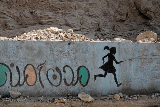 A mural in Cairo depicting the silhouette of a girl running, and anti-sexual harassment message in Arabic reading 'Safe cities'