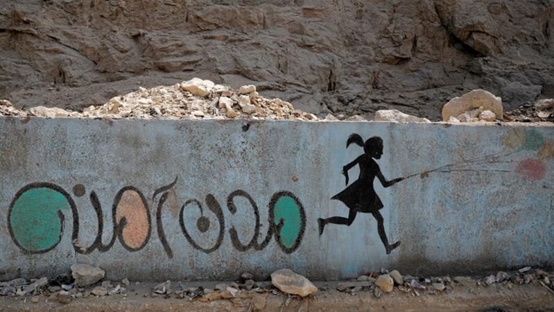 A mural in Cairo depicting the silhouette of a girl running, and anti-sexual harassment message in Arabic reading 'Safe cities'