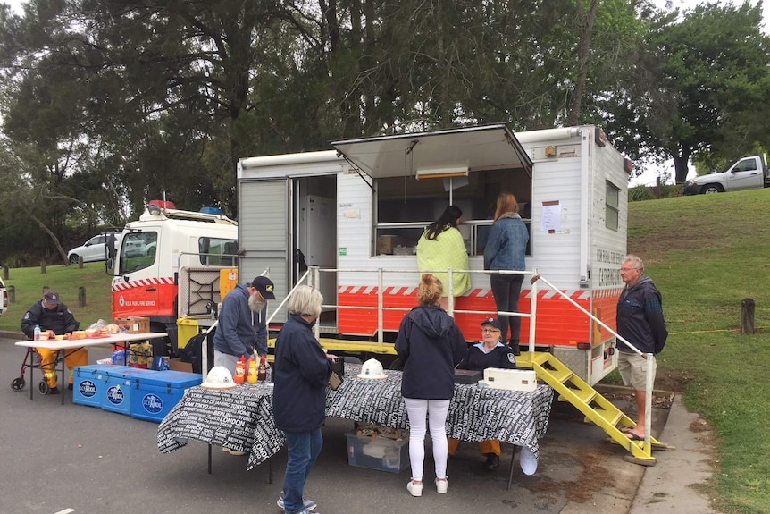 Red RFS catering van parked on fire site with people lining up for lunch.