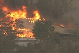 A building can be seen from above, engulfed in flames