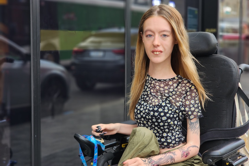 A young white woman in a wheelchair out on the street