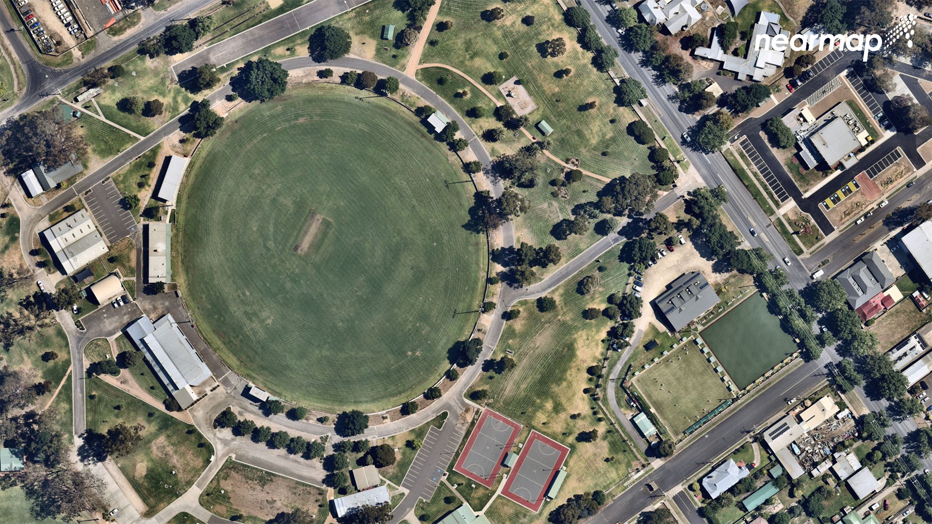 The picture shows a footy oval from above, with parkland with some housing around it