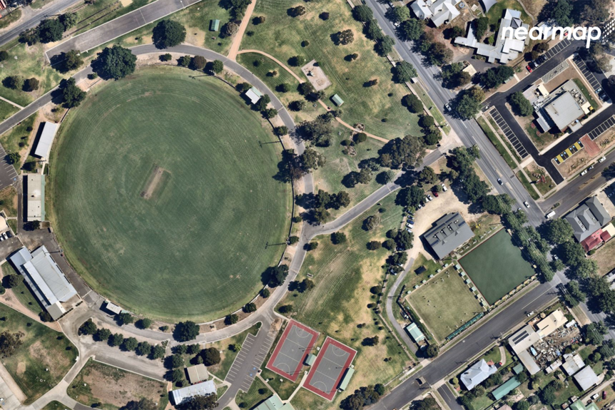 The picture shows a footy oval from above, with parkland with some housing around it