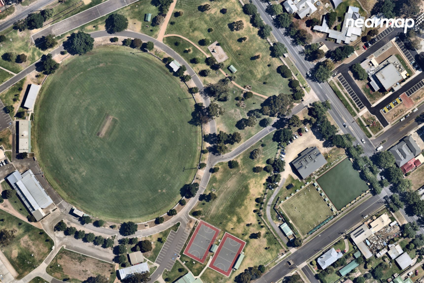 The picture shows a footy oval from above, with parkland with some housing around it