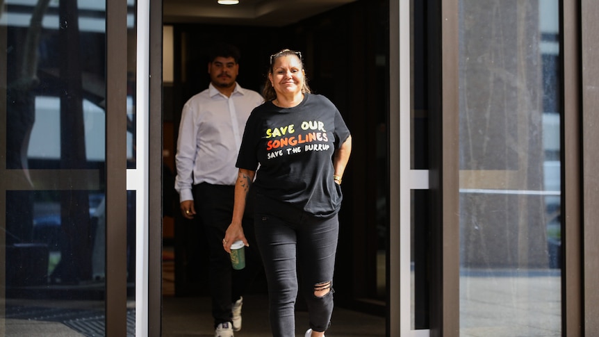 Raelene Cooper smiles as she walks out the doors of a court