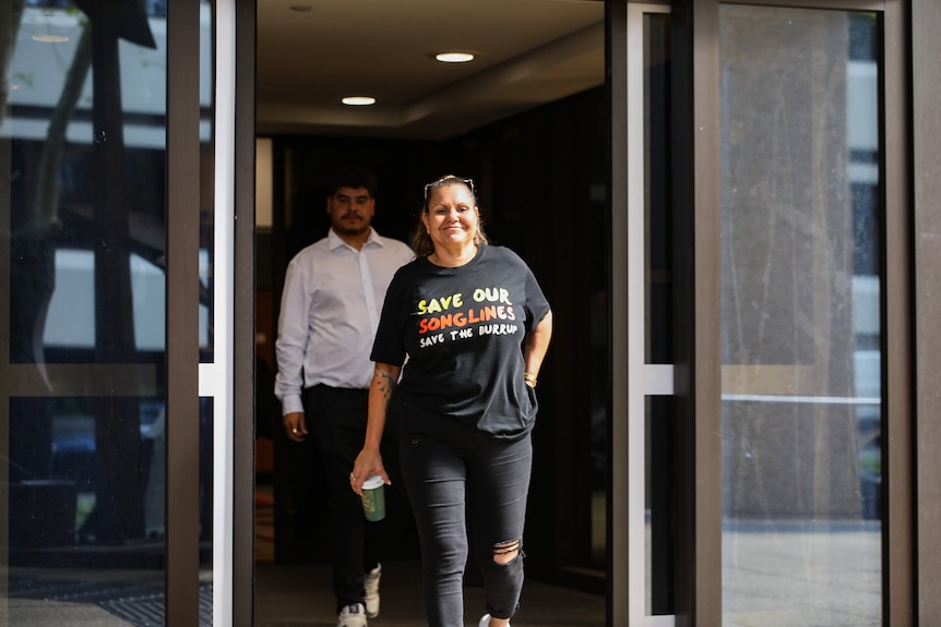 Raelene Cooper smiles as she walks out the doors of a court