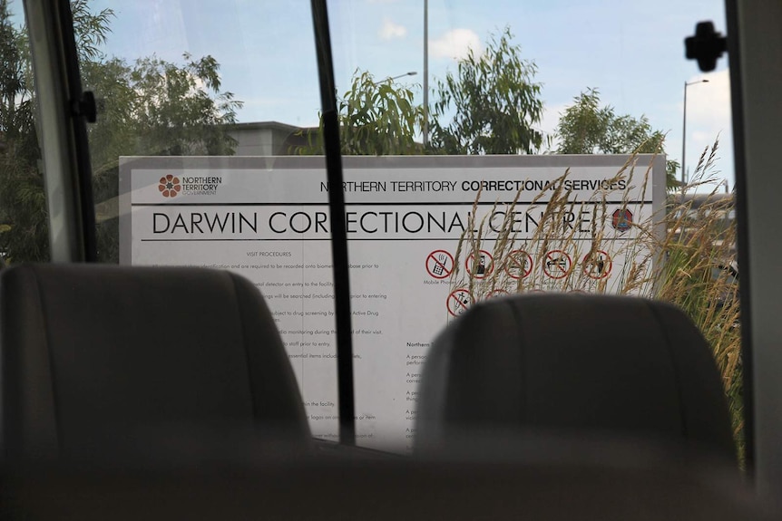 A photo of the Darwin Correctional Centre sign, visible through a bus window.