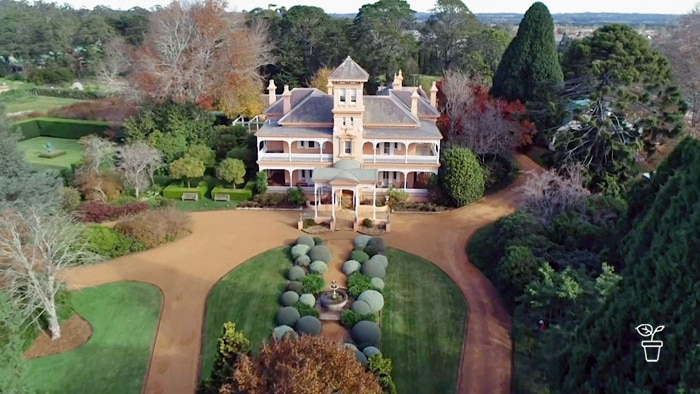 Aerial view of large grand house surrounded in formal gardens