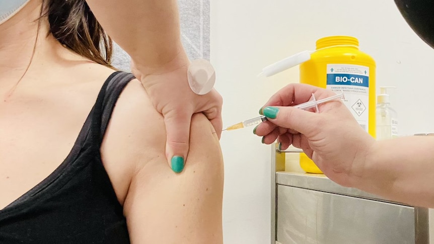 A close-up of a needle going into a woman's arm.