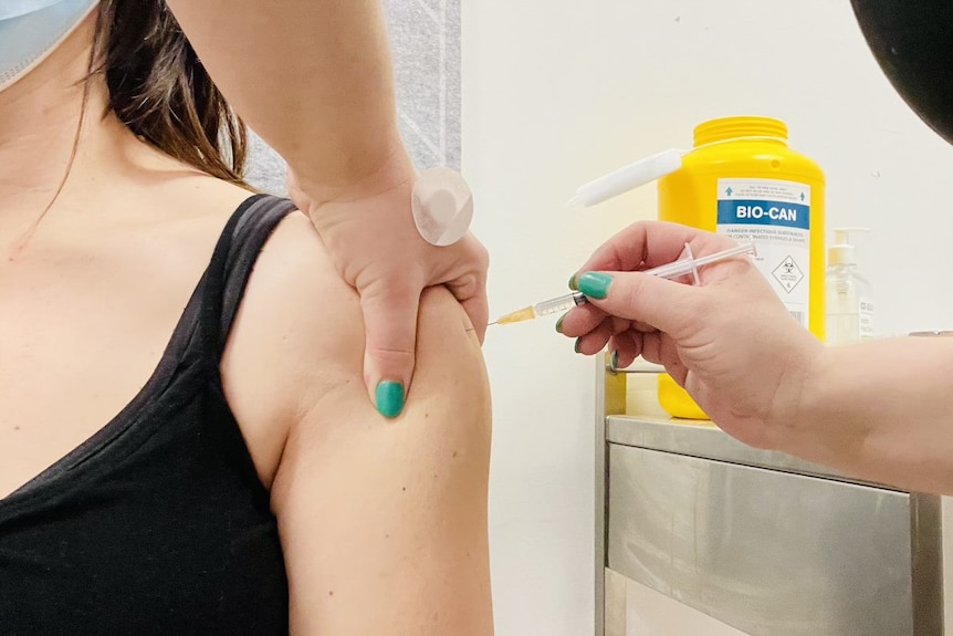 A close-up of a needle going into a woman's arm.