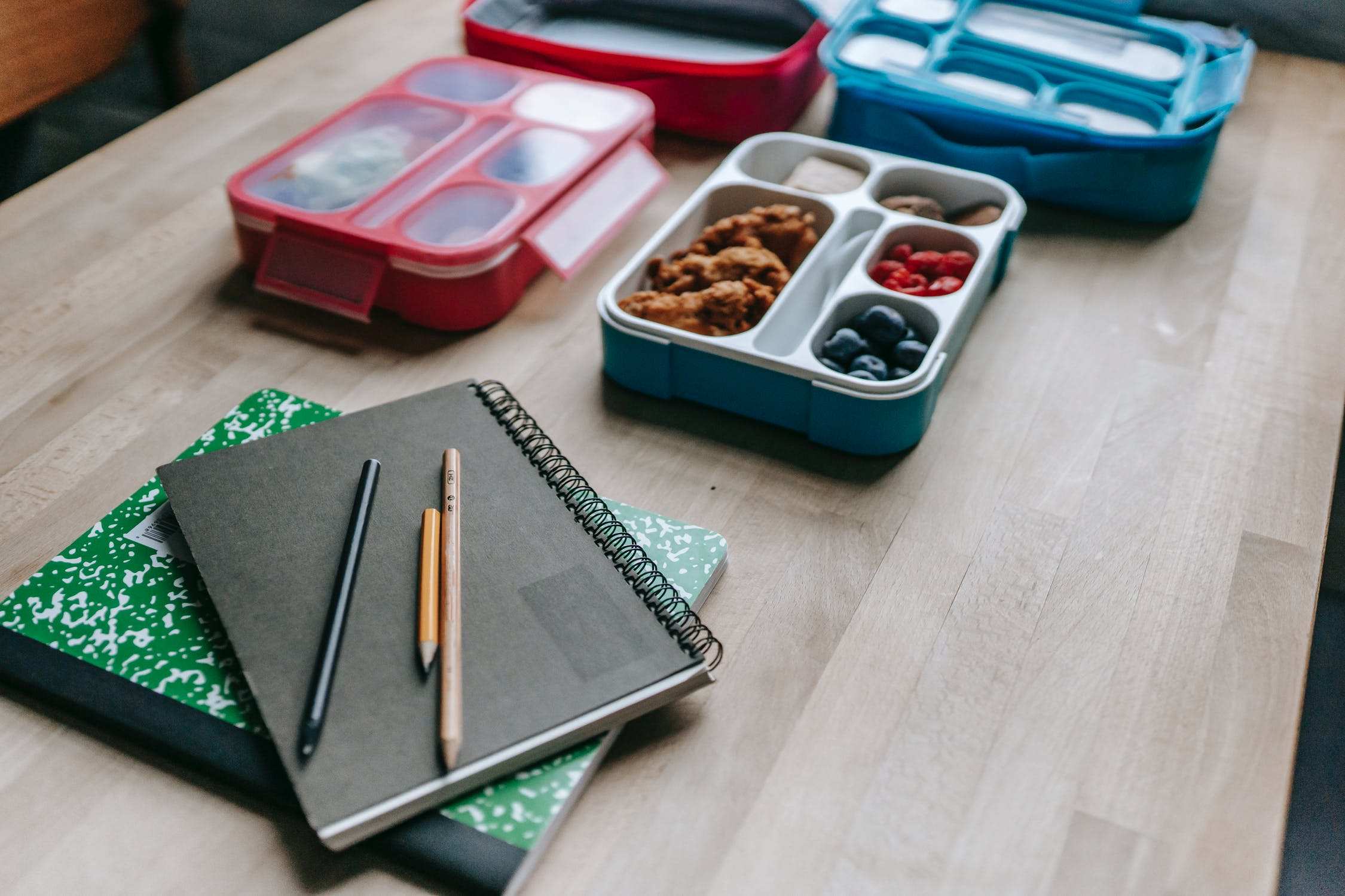 Lunch boxes and school books on a table.