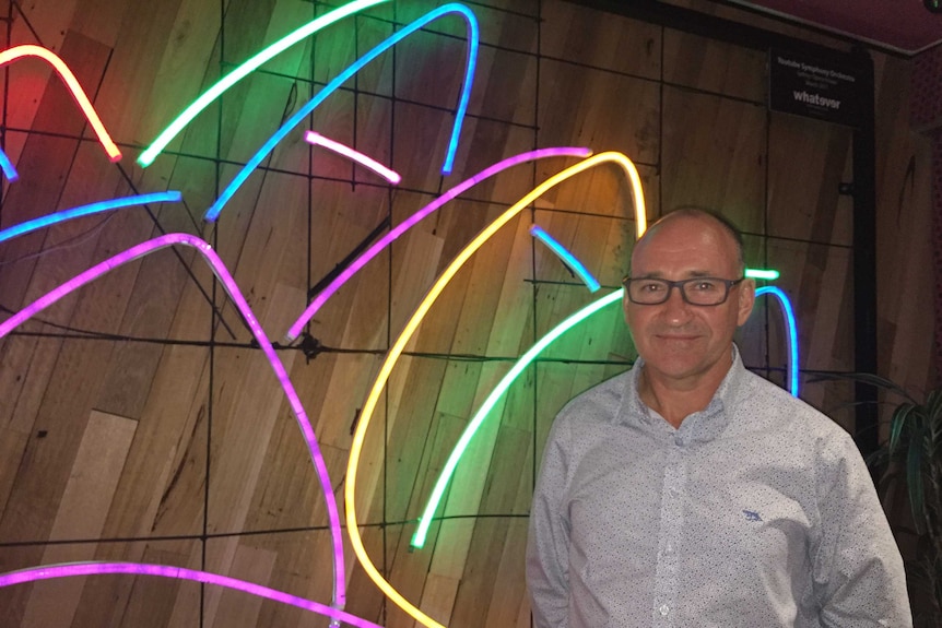 Coloured neon lights of Sydney Opera House with man standing at Google head office in Sydney