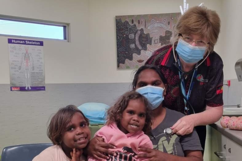 A health worker stands with patients in a remote NT clinic.