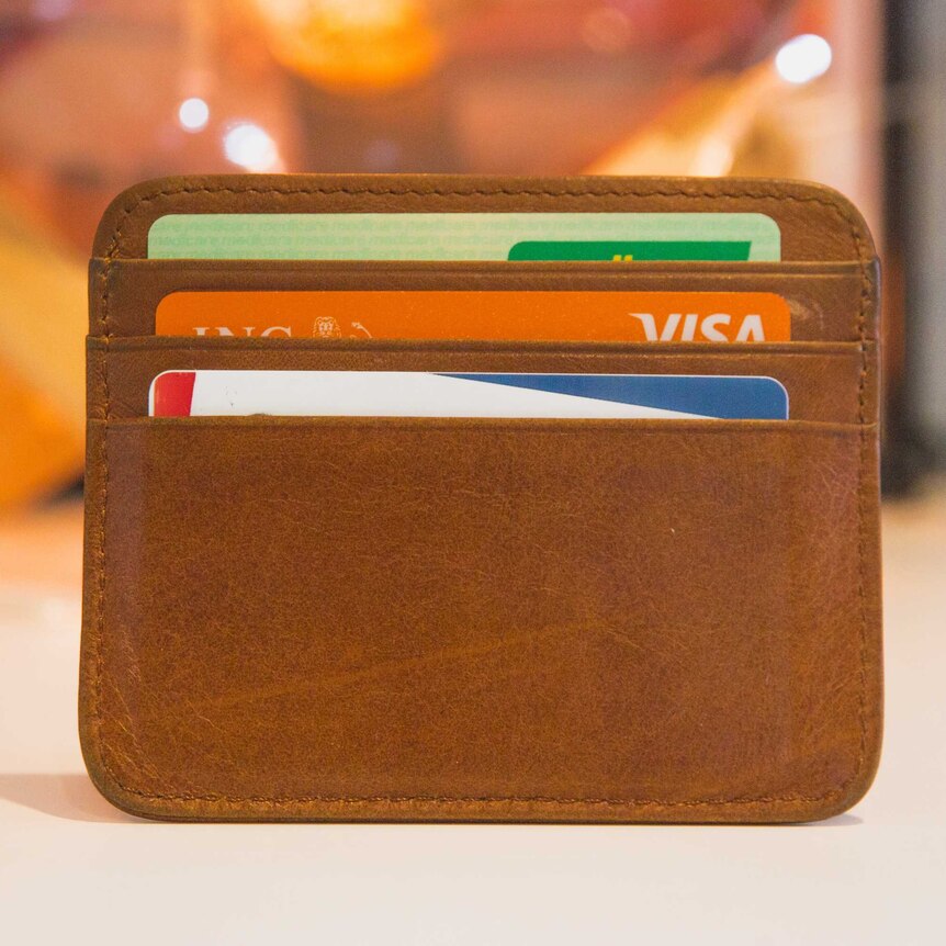 A wallet holds three cards including an ATM card