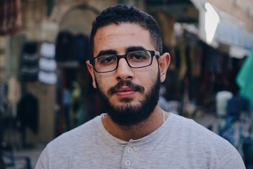 Jonathan Abu Ali wears glasses as he stands in a busy thoroughfare in Jerusalem's old city