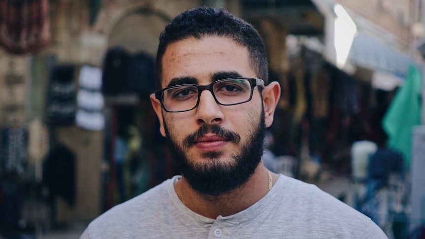 Jonathan Abu Ali wears glasses as he stands in a busy thoroughfare in Jerusalem's old city