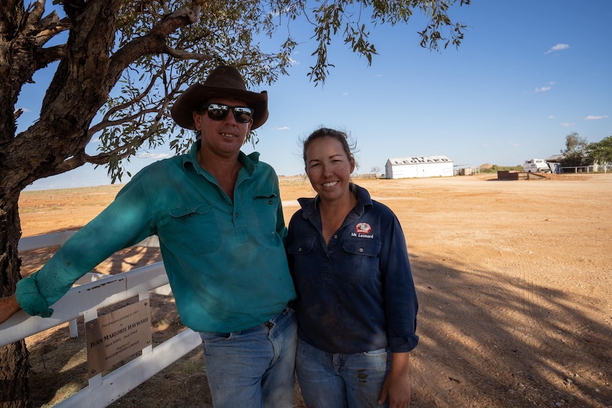 A man and woman in dusty clothes stand outside and smile at the camera