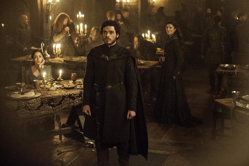 Talisa sits at the banquet table, as Robb and Catelyn stand looking worried
