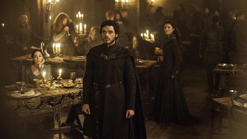 Talisa sits at the banquet table, as Robb and Catelyn stand looking worried