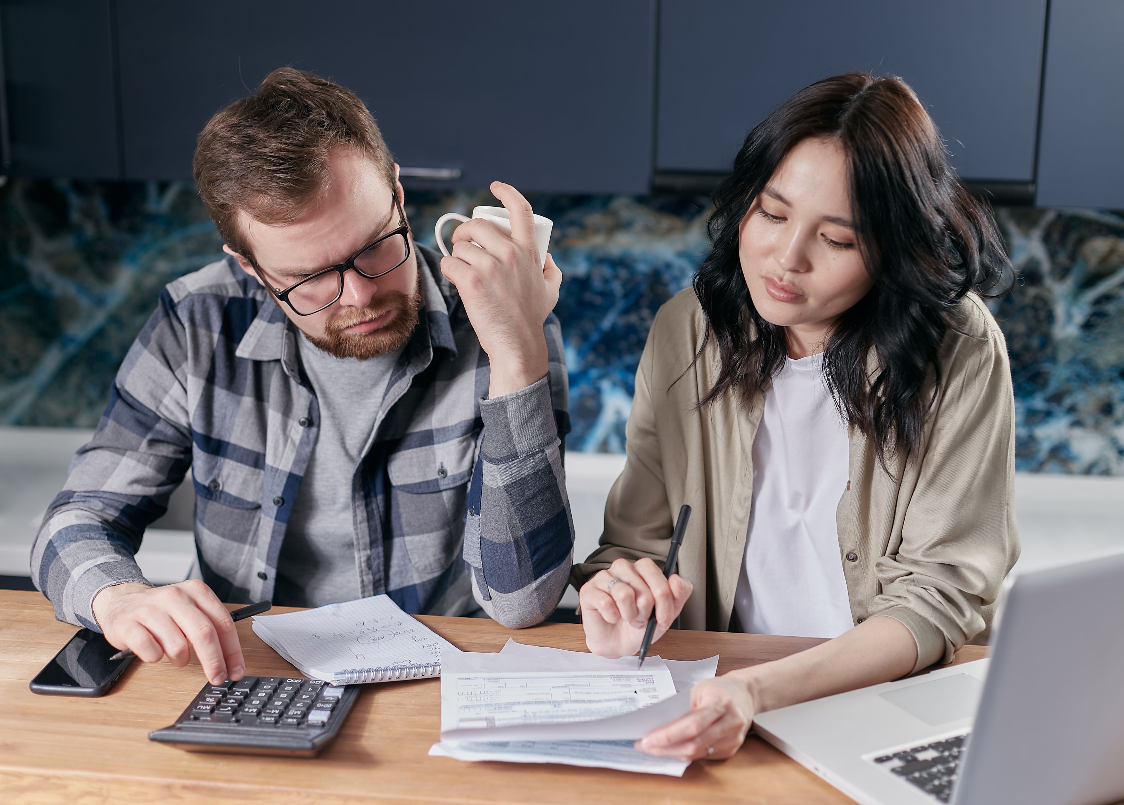 A man and a woman looking at bills and receipts at a kitchen table.