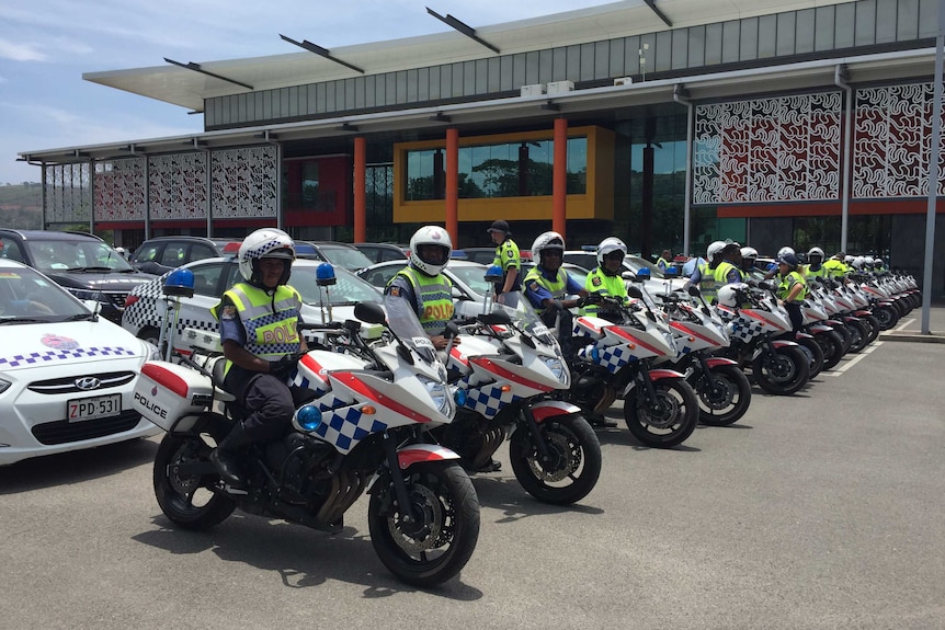 police on police motorbikes line up in a row outside a building