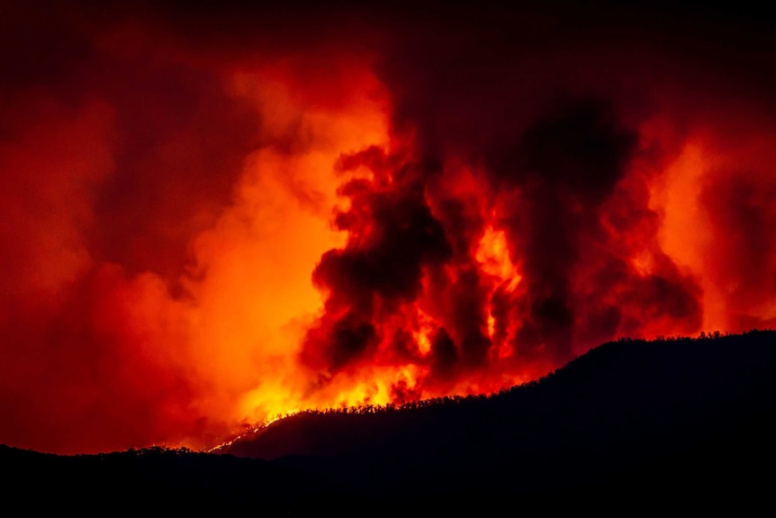 A fire burns beyond a mountain range in Namadgi National Park as seen from Mount Stromlo Observatory, January 28, 2020.