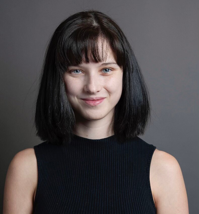 A professional portrait of a woman with fair skin and short black hair smiling 