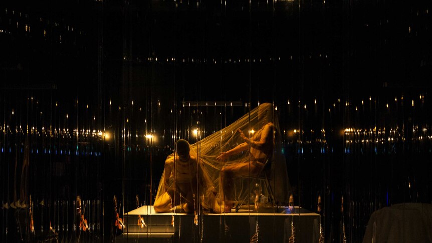 Two figures on stage obscured and shrouded in material