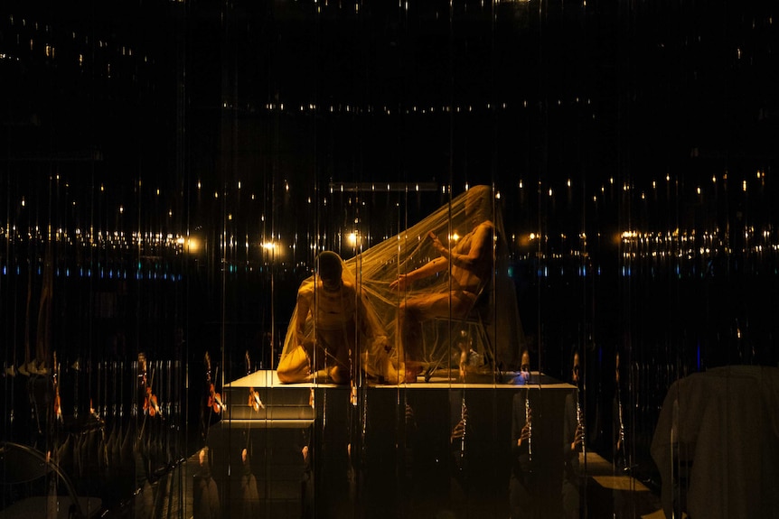 Two figures on stage obscured and shrouded in material