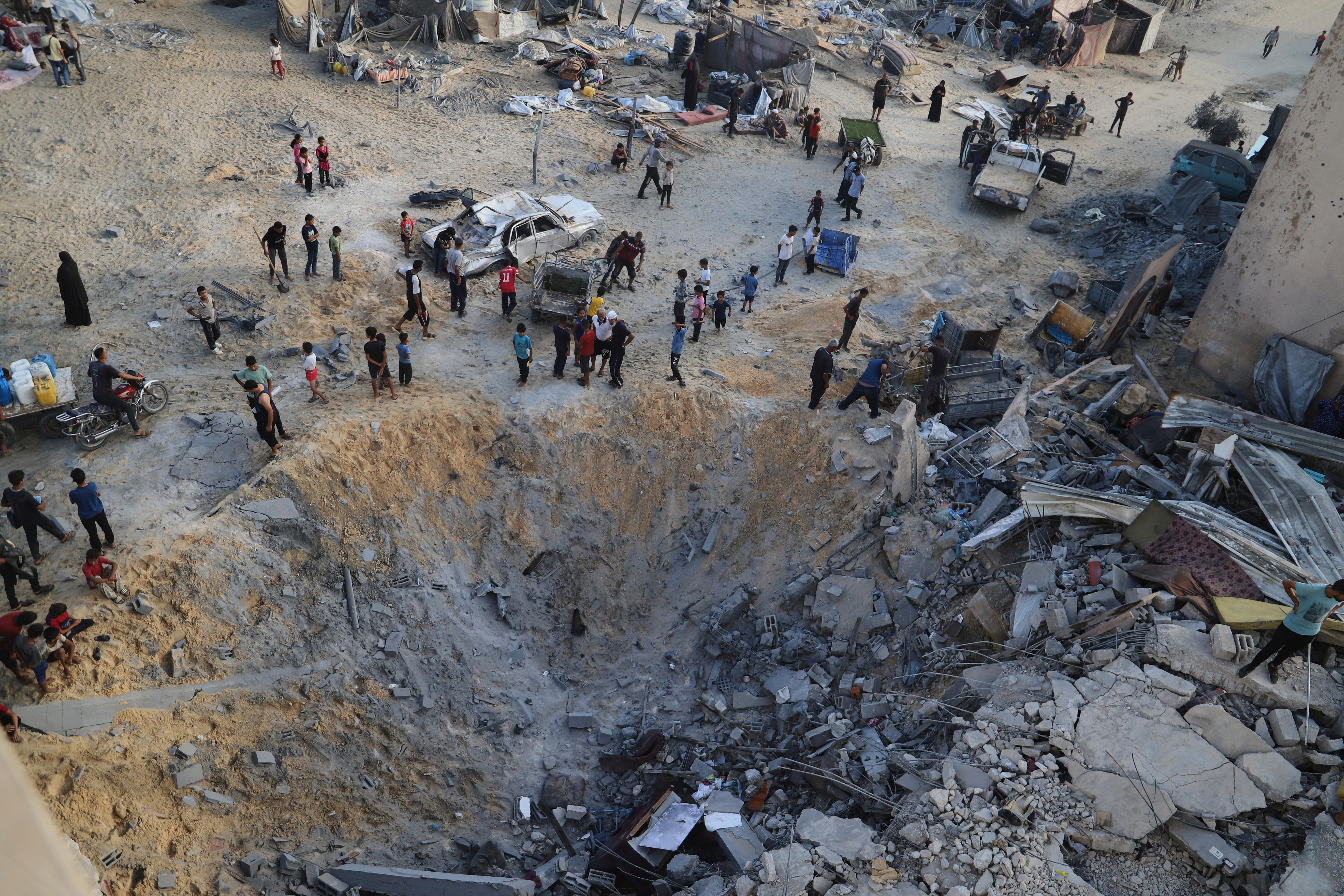 Palestinians inspect the site struck by an Israeli bombardment