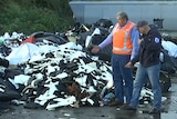Men stand near a garbage pile