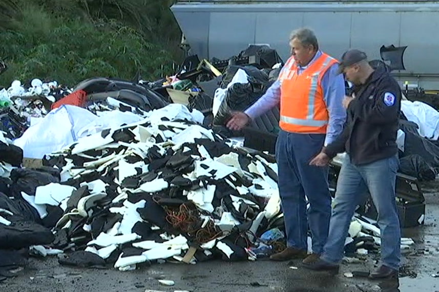 Men stand near a garbage pile