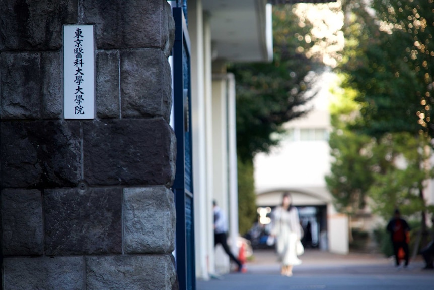 Anonymous woman walking past university gates