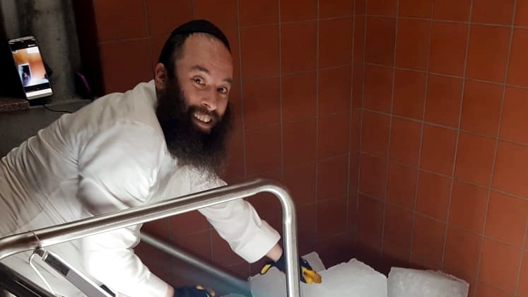 Photograph of a smiling rabbi with blocks of ice