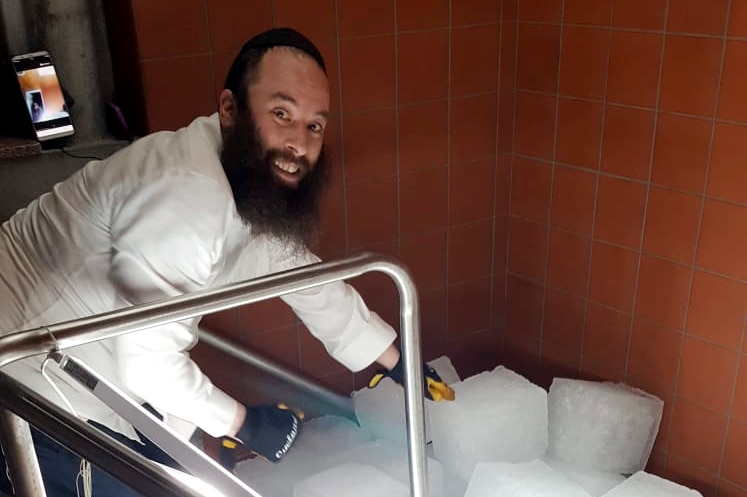 Photograph of a smiling rabbi with blocks of ice