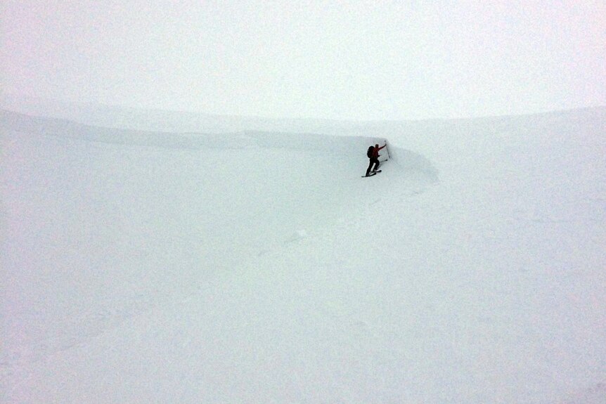 A skier is seen standing on the side of a mountain covered in snow.