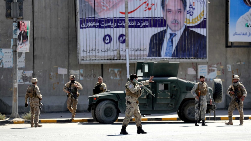 Afghan security forces work at the site of a suicide attack near the US Embassy in Kabul. Election posters are on the walls.