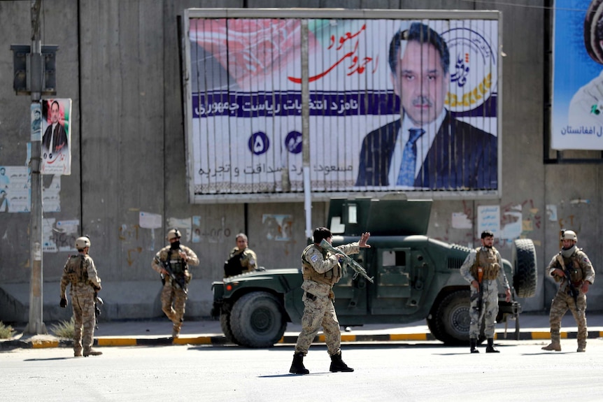 Afghan security forces work at the site of a suicide attack near the US Embassy in Kabul. Election posters are on the walls.