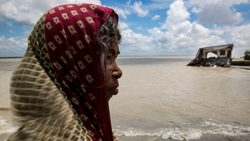 Woman near eroded home in Bangladesh