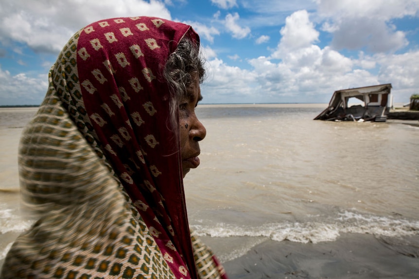 Woman near eroded home in Bangladesh