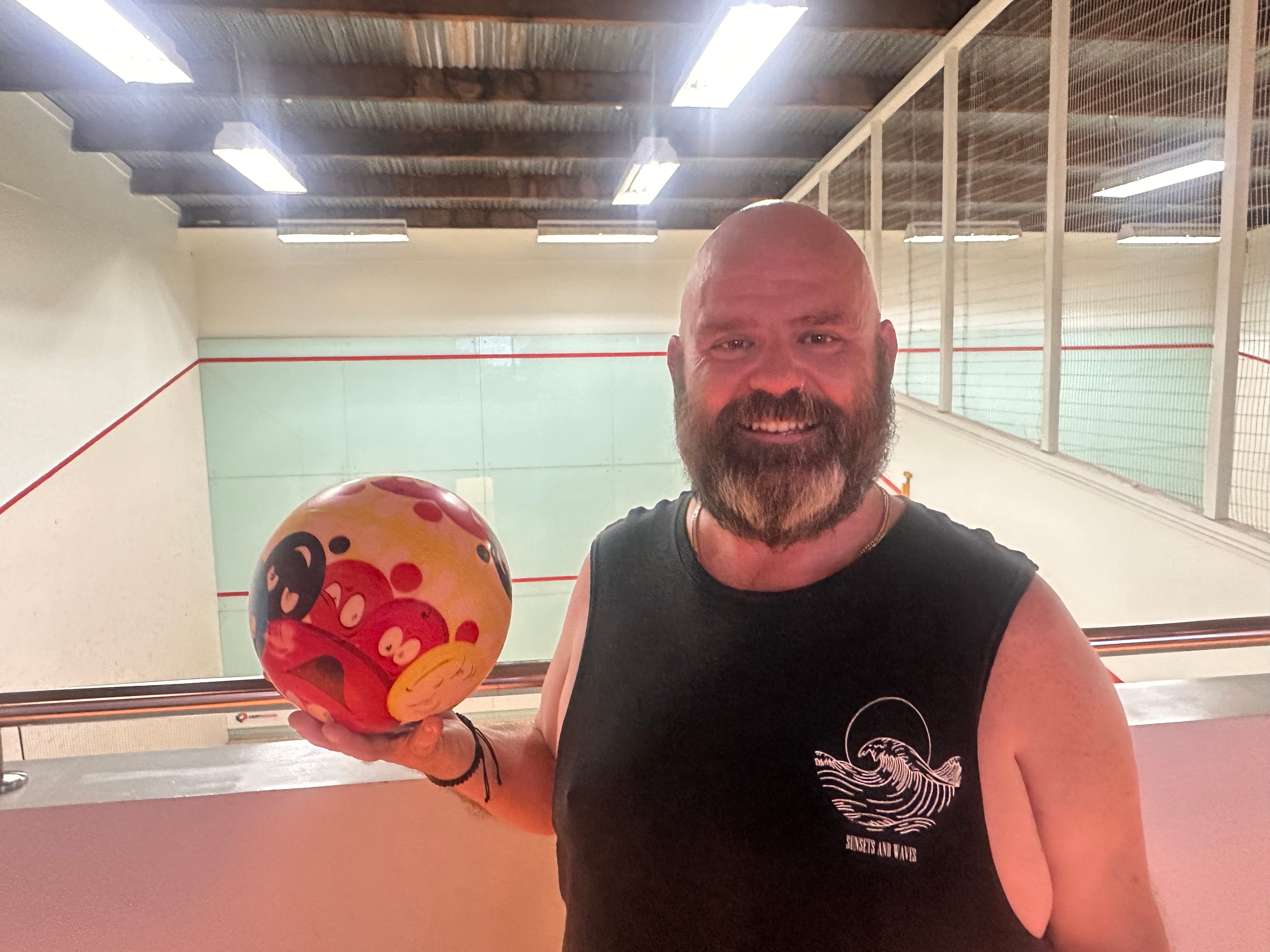 um homem careca segurando uma bola de vôlei