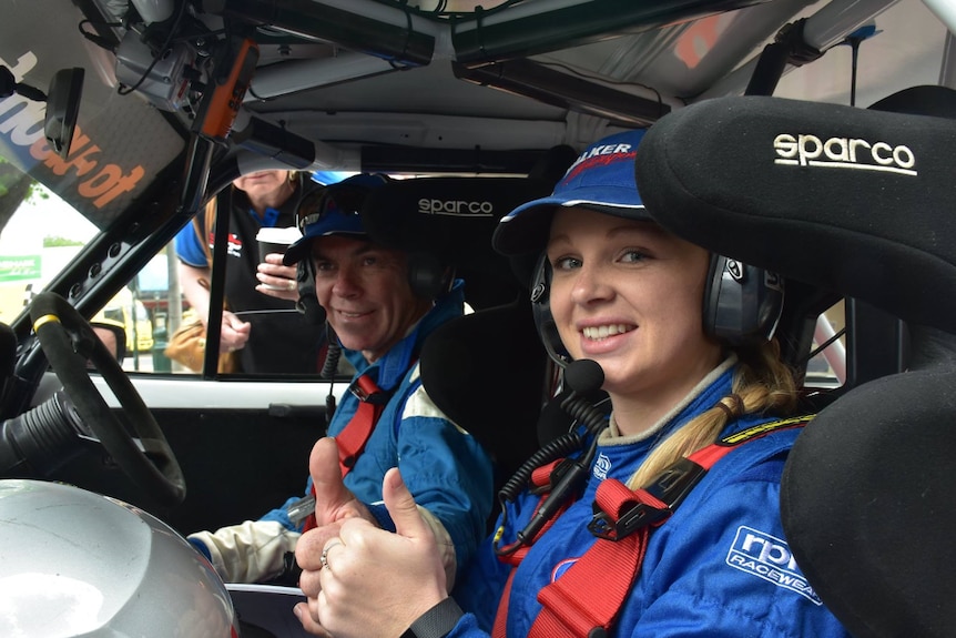 The interior of a rally car with Grant Walker and Stephanie Richards smiling at the camera