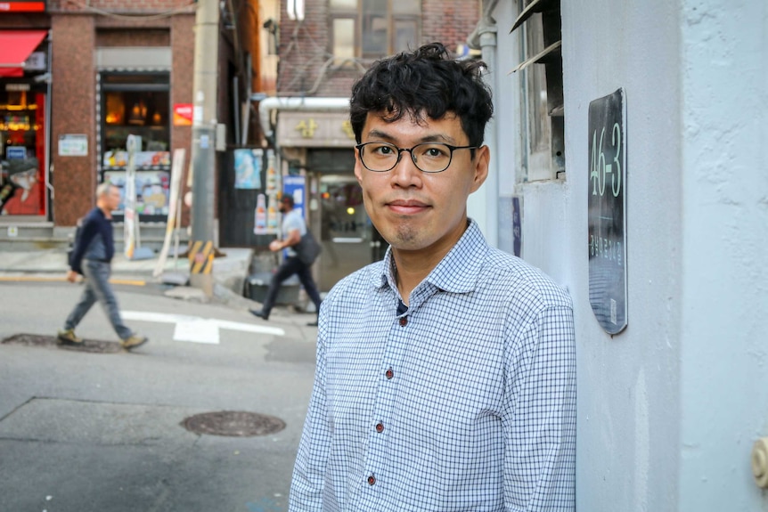 A man in side street looks towards the camera