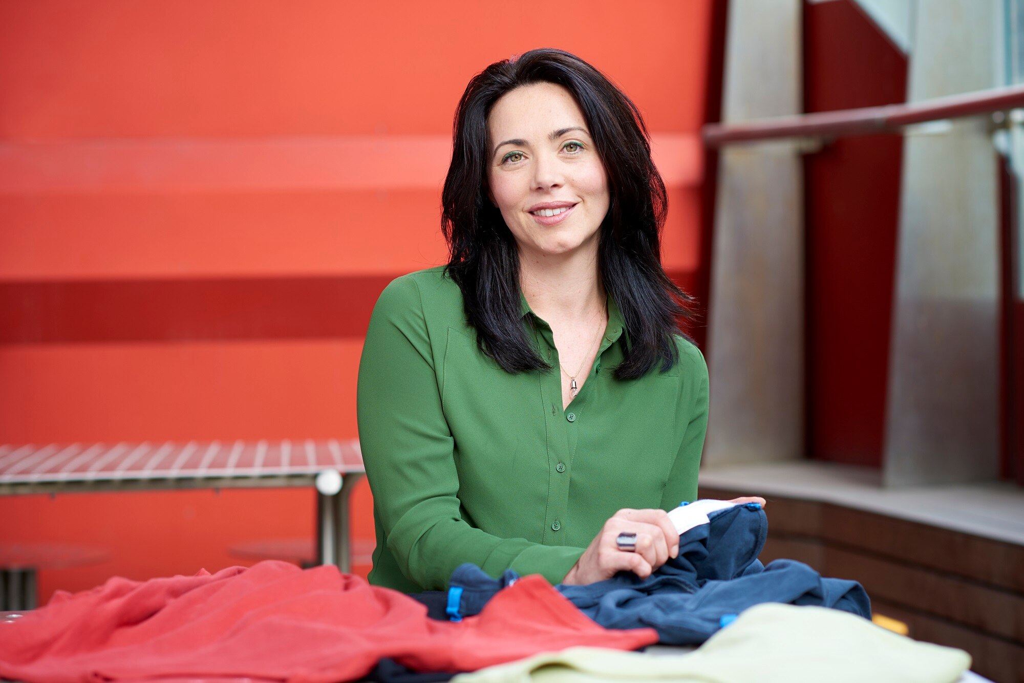 A brunette woman sits at a table holding a fabric swatch.