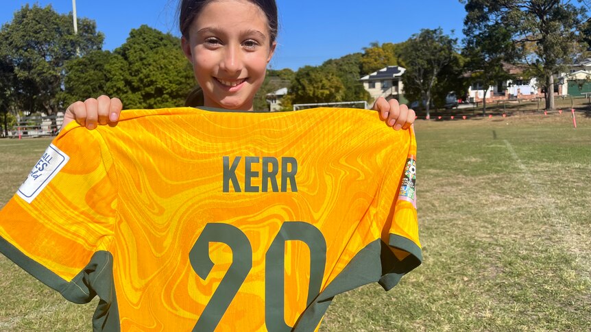 A young girl holds up a jersey printed with the name Kerr 