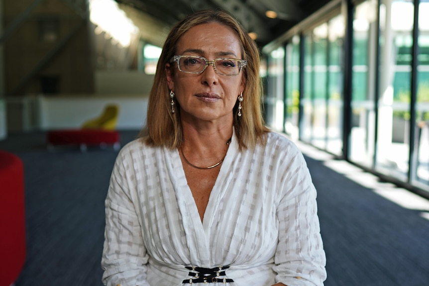 A woman wearing glasses and a white top.